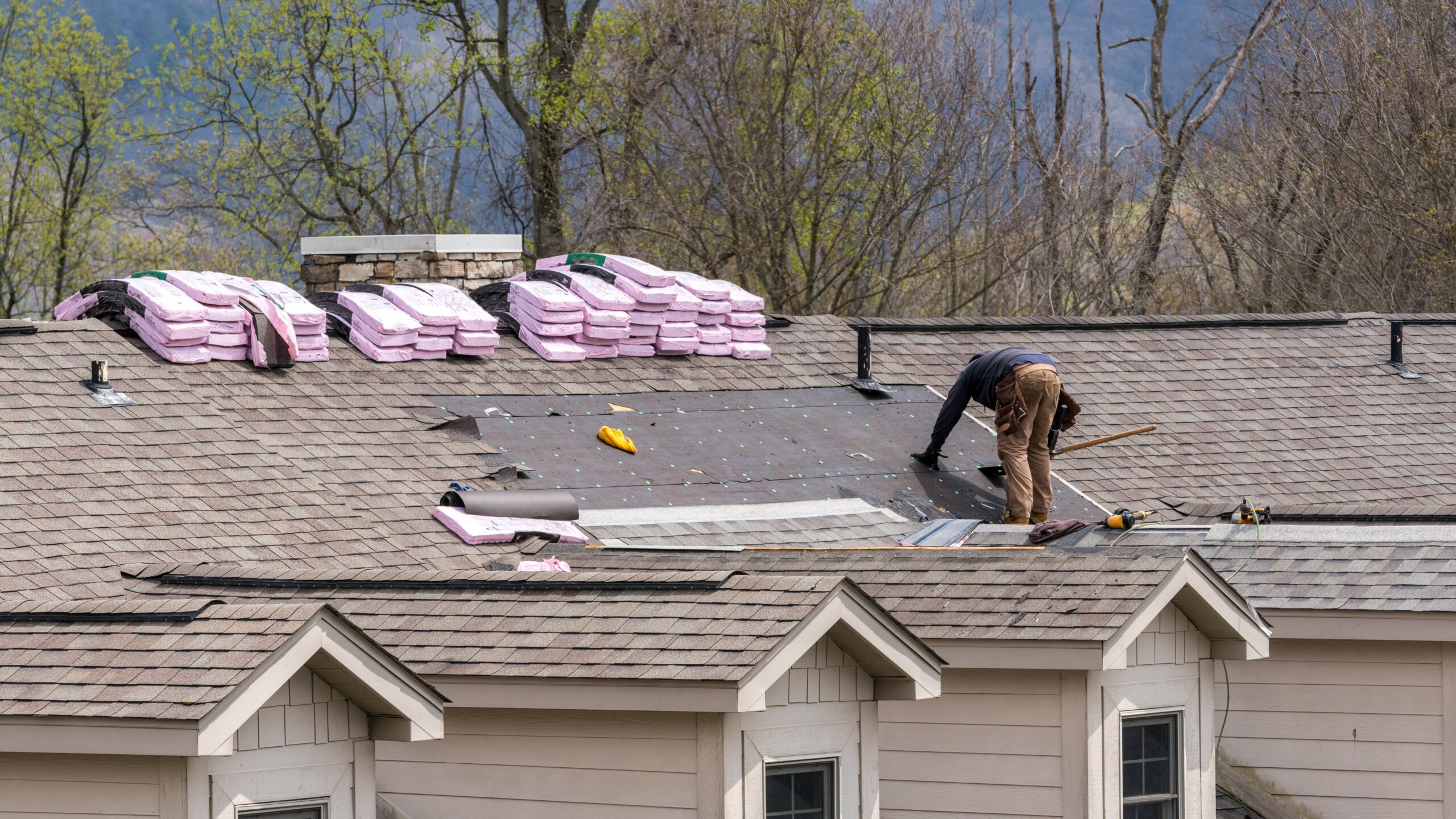 roofing laborer installing shingle roof.