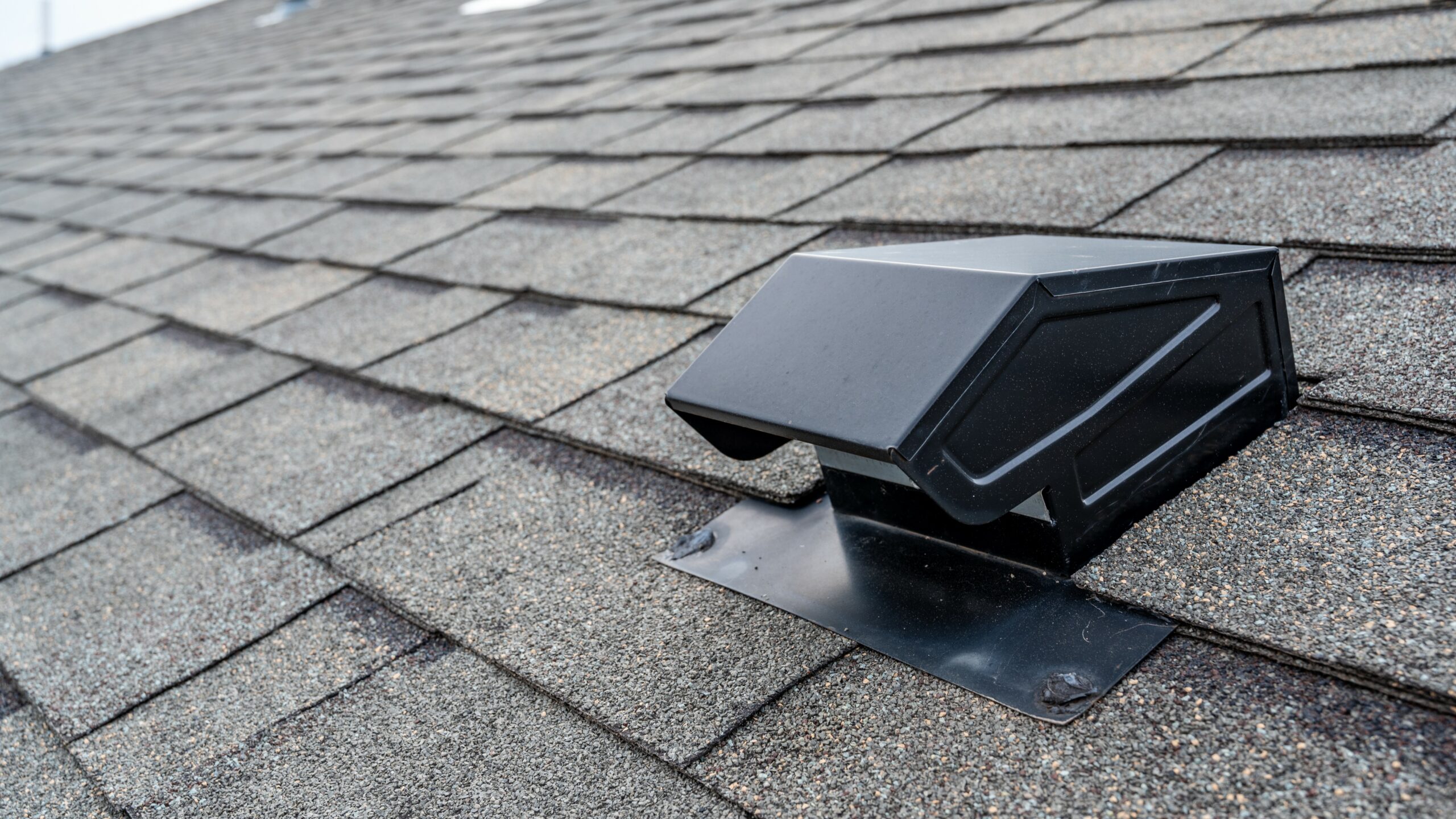 black static vent on brown shingle roof.