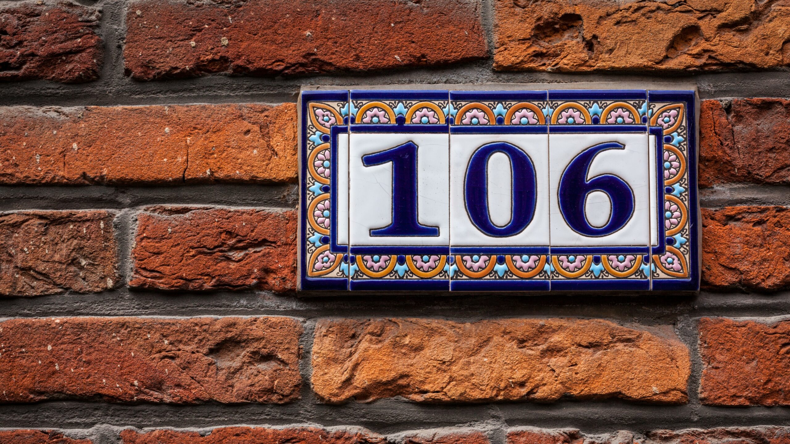 Decorated house number on brick wall